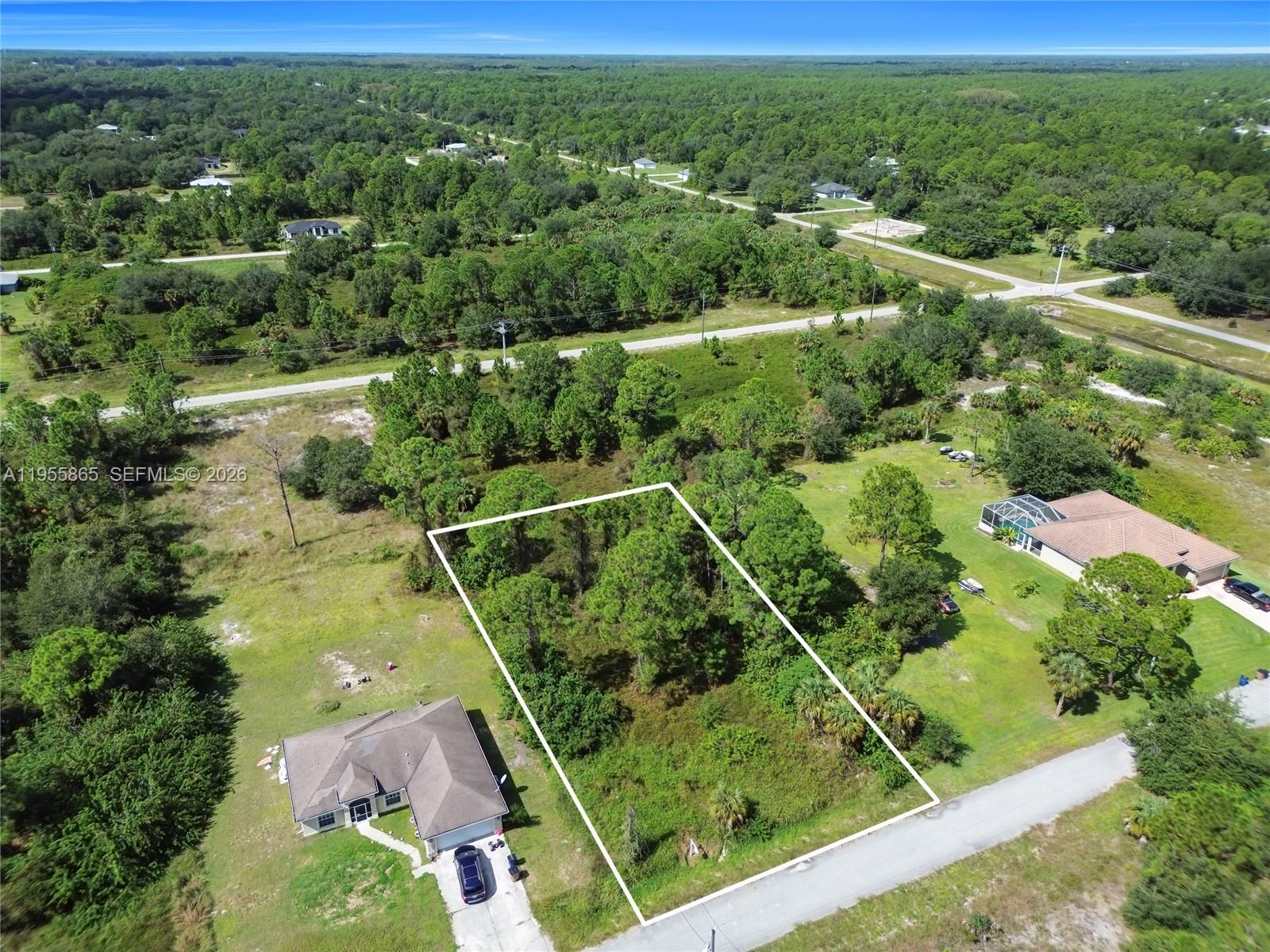 An aerial view shows a vacant, rectangular residential lot outlined in white between two houses — 1915 Louis Ave, Lehigh Acres FL 33972, LEHIGH ACRES, FL