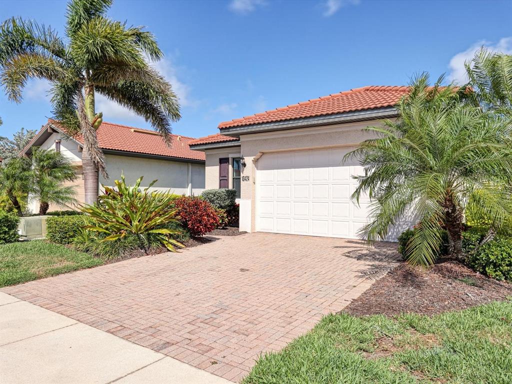 A single-story house with a tiled roof, a two-car garage, and palm trees in the yard — 10424 CROOKED CREEK DRIVE, VENICE, FL
