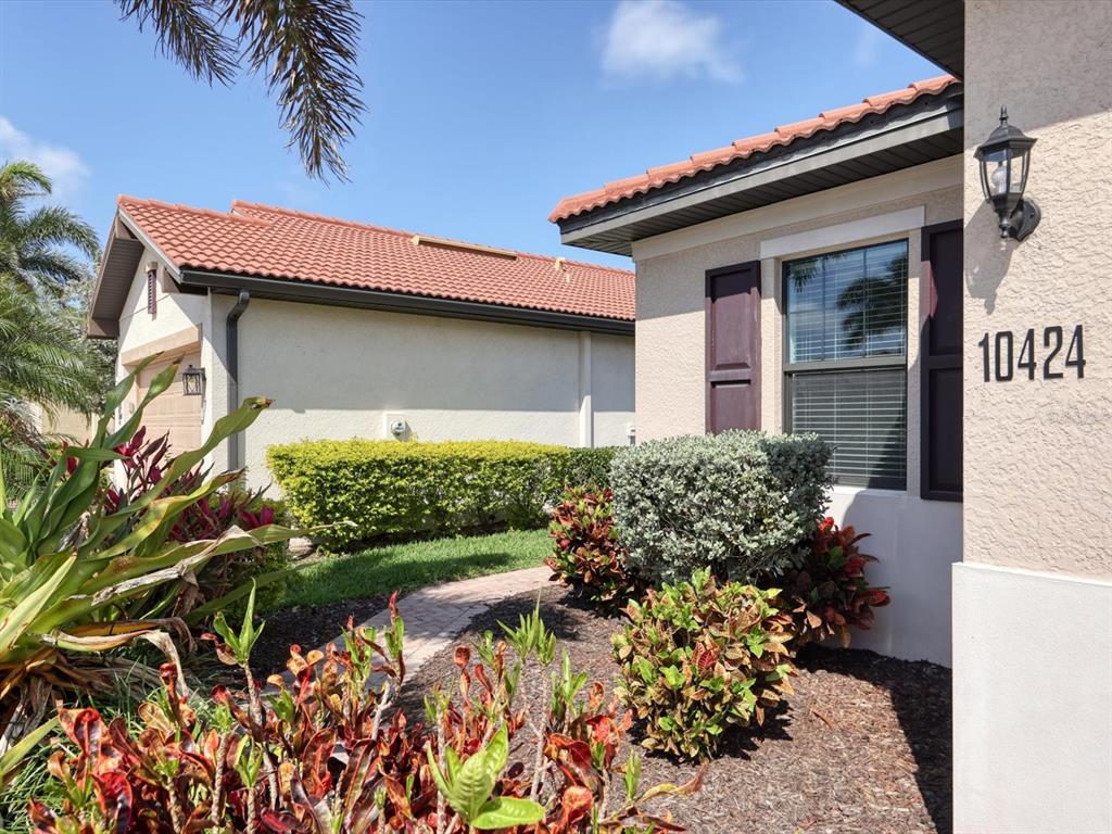 A view of a house exterior with a tiled roof, landscaping, and a brick walkway — 10424 CROOKED CREEK DRIVE, VENICE, FL
