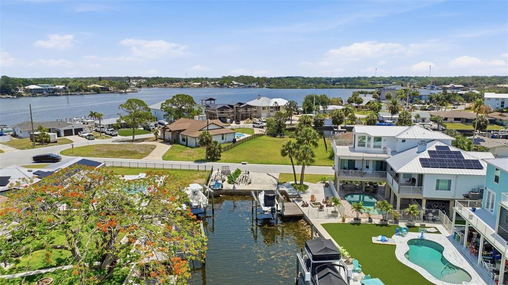 An aerial view shows waterfront homes with private docks, swimming pools, and solar panels — 8126 BRIGHTON DRIVE, PORT RICHEY, FL