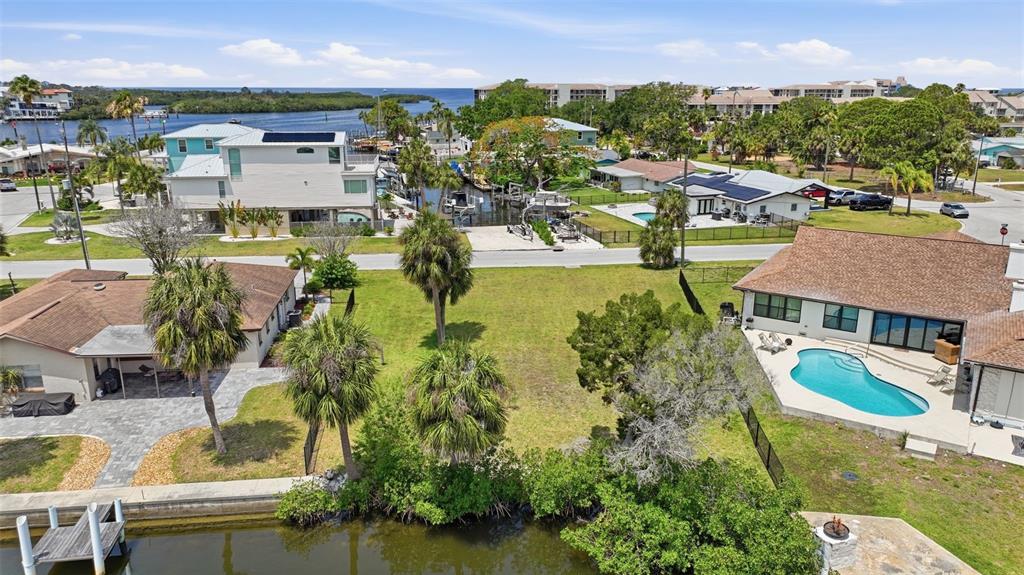 An aerial view shows a vacant waterfront lot situated between two houses with swimming pools — 8126 BRIGHTON DRIVE, PORT RICHEY, FL
