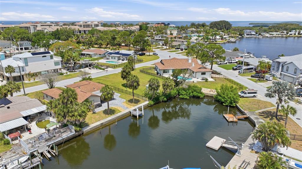 An aerial view shows waterfront houses with pools, docks, and palm trees along a canal — 8126 BRIGHTON DRIVE, PORT RICHEY, FL
