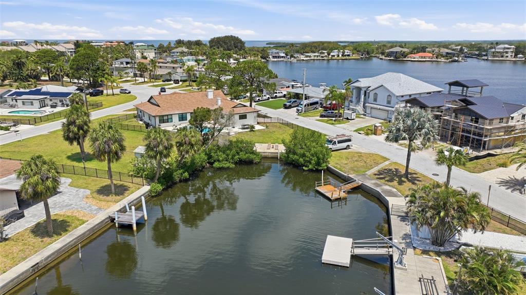 An aerial view shows waterfront homes with docks along a canal near the open water — 8126 BRIGHTON DRIVE, PORT RICHEY, FL