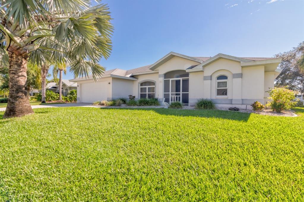 A single-story house with a screened entryway, a two-car garage, and a palm tree — 26 LONG MEADOW LANE, ROTONDA WEST, FL