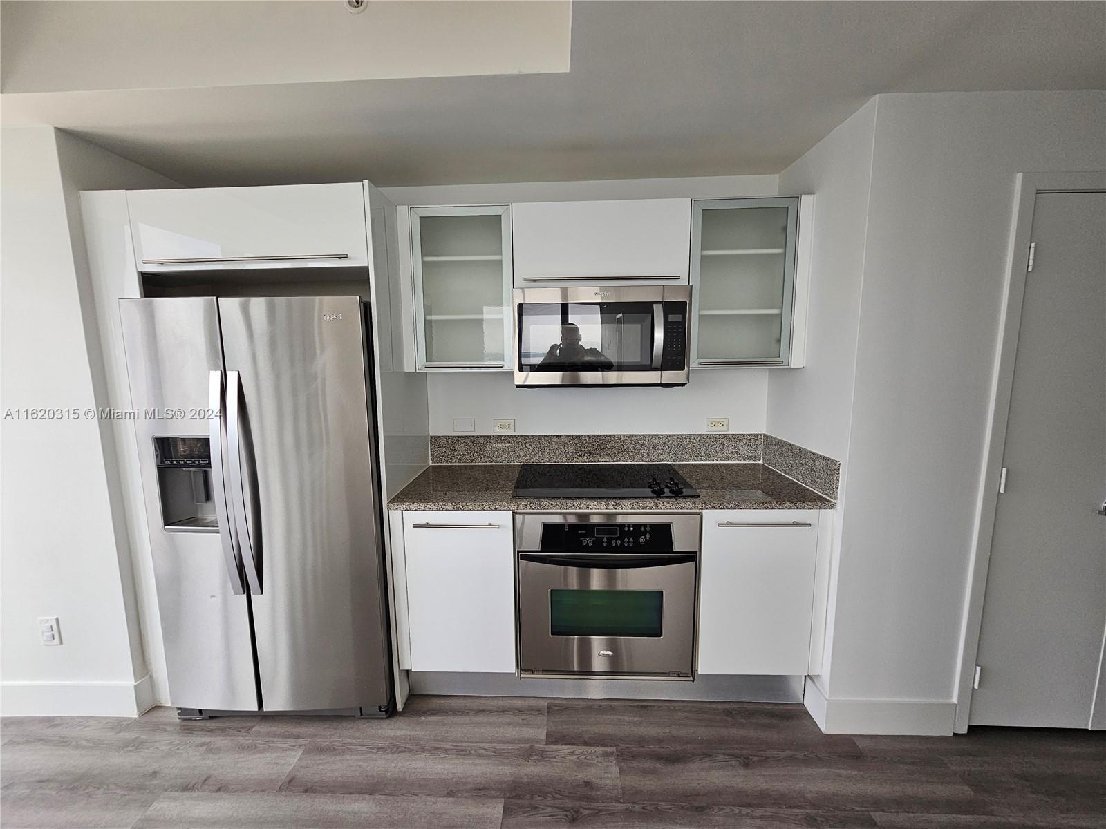 A modern kitchen features stainless steel appliances, white cabinetry, and granite countertops — 888 Biscayne Blvd # 4001, Miami FL 33132, MIAMI, FL