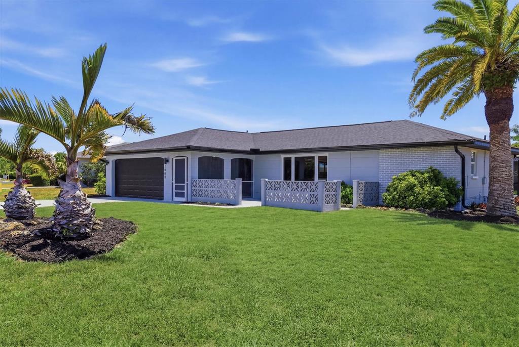 A single-story house with a garage, decorative concrete block walls, and palm trees in front — 1600 CYPRESS POINT COURT, VENICE, FL