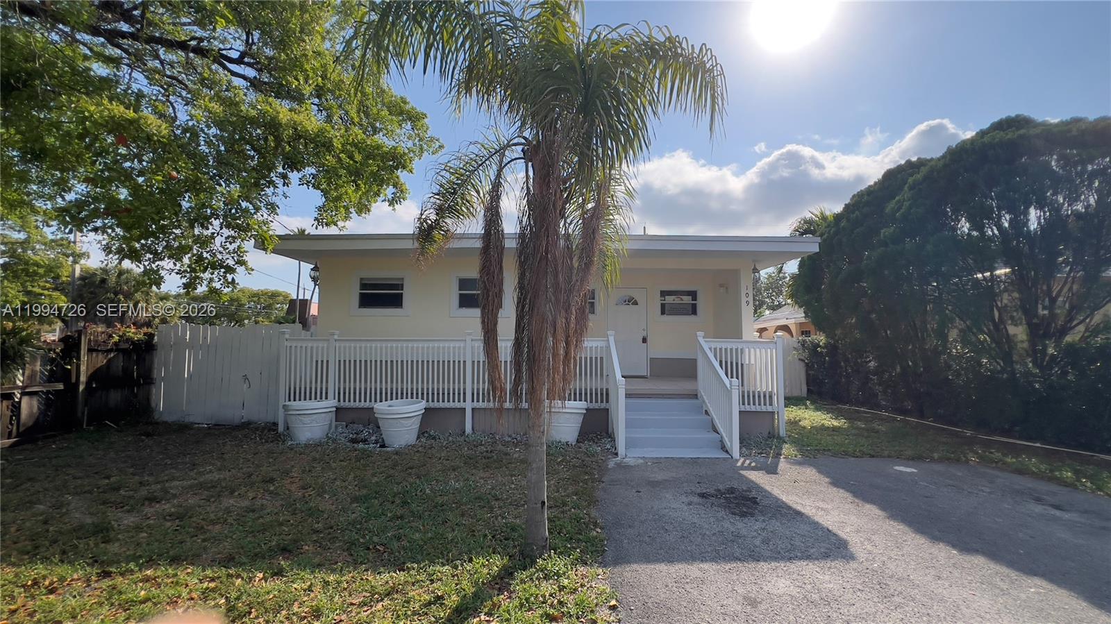 A single-story house with a white porch, a palm tree, and a paved driveway — 109 SW 1st Ave, Hallandale Beach FL 33009, HALLANDALE BEACH, FL