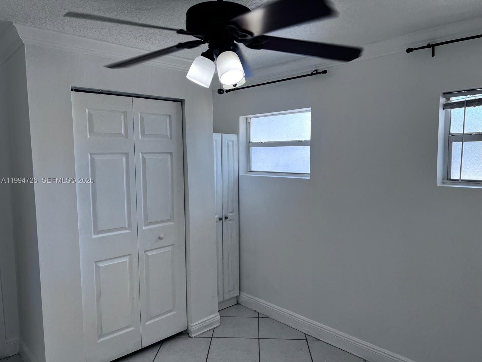 A room with white walls, tiled floors, a ceiling fan, and two windows — 109 SW 1st Ave, Hallandale Beach FL 33009, HALLANDALE BEACH, FL