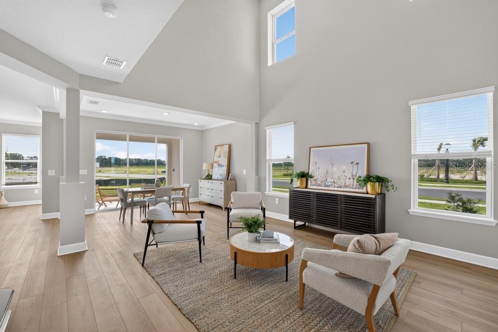 A bright, open-concept living and dining area features high ceilings, light wood floors, and windows — 5073 LOST KEY PLACE, ST CLOUD, FL