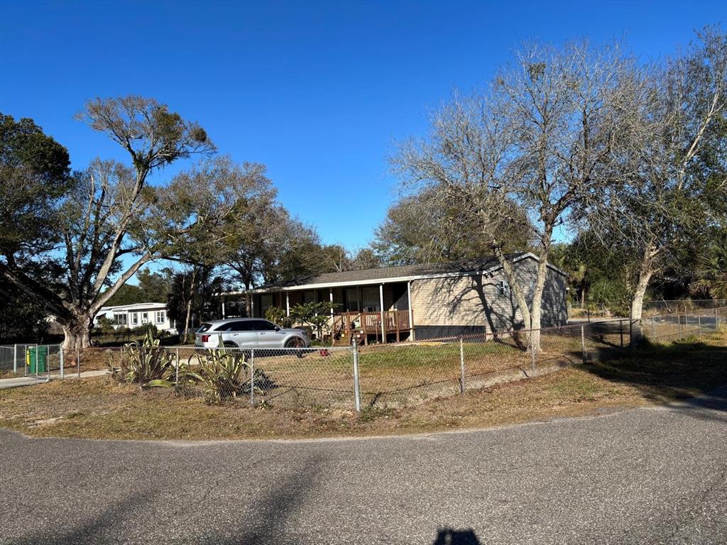 A single-story manufactured home with a front porch sits behind a chain-link fence — 3303 TURNBULL ROAD, MIMS, FL