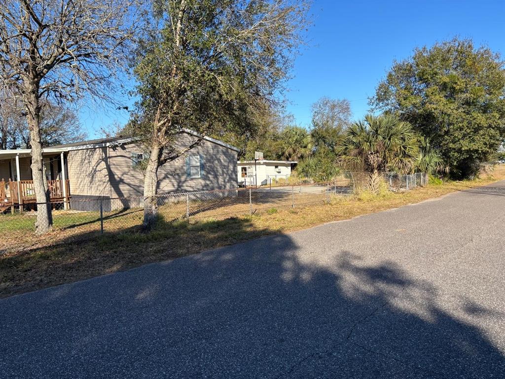 A single-story manufactured home sits behind a chain-link fence next to a paved road — 3303 TURNBULL ROAD, MIMS, FL