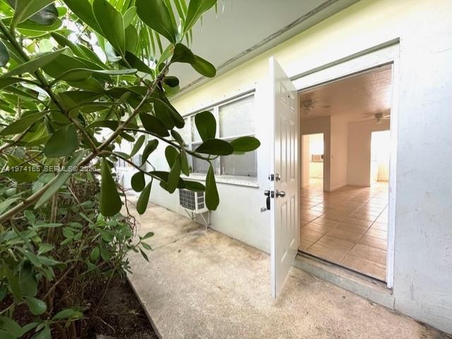 An open white door leads from a concrete walkway into a tiled interior space — 810 82nd St, Miami Beach FL 33141, MIAMI BEACH, FL