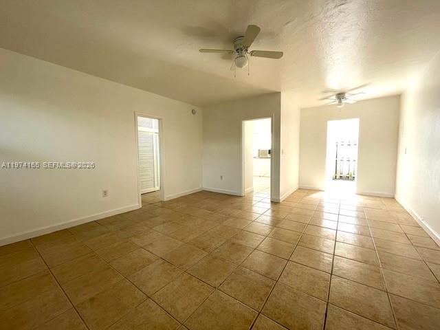 An empty room features beige tile flooring, white walls, and two ceiling fans — 810 82nd St, Miami Beach FL 33141, MIAMI BEACH, FL