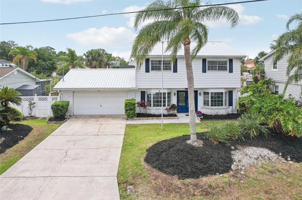 A two-story white house with a metal roof, a garage, and a palm tree — 8706 ELMWOOD LANE, TAMPA, FL