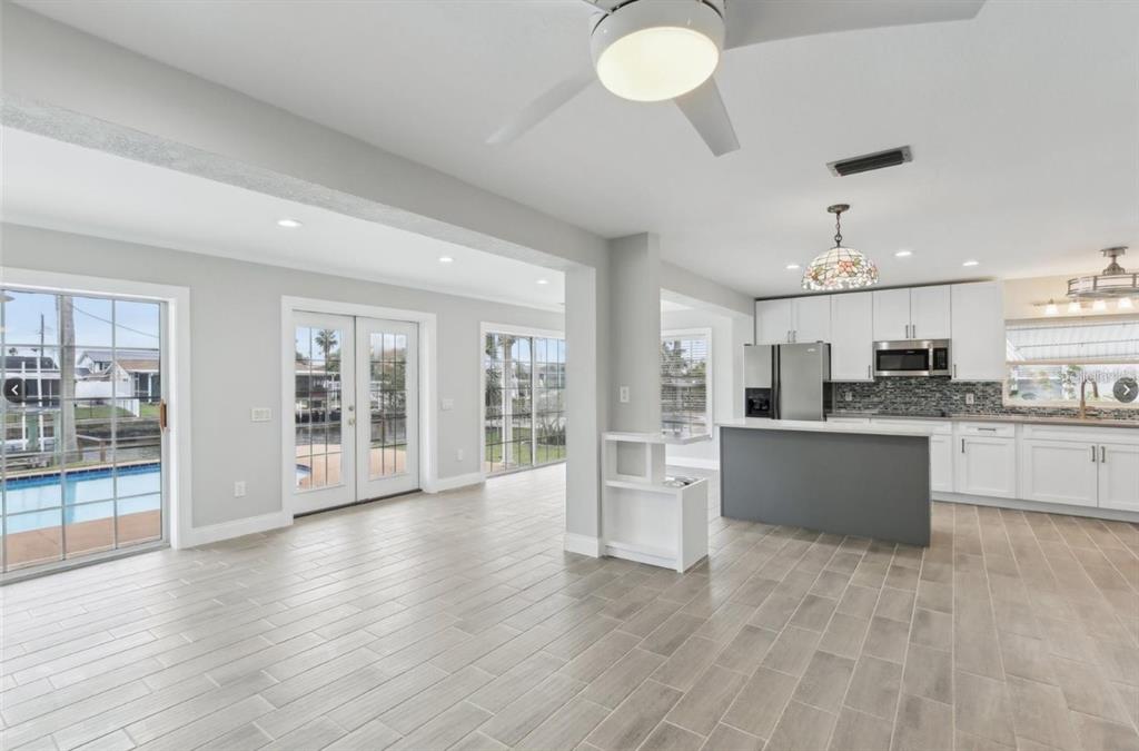 A bright open-concept kitchen and living area with light tile floors and a pool view — 8706 ELMWOOD LANE, TAMPA, FL