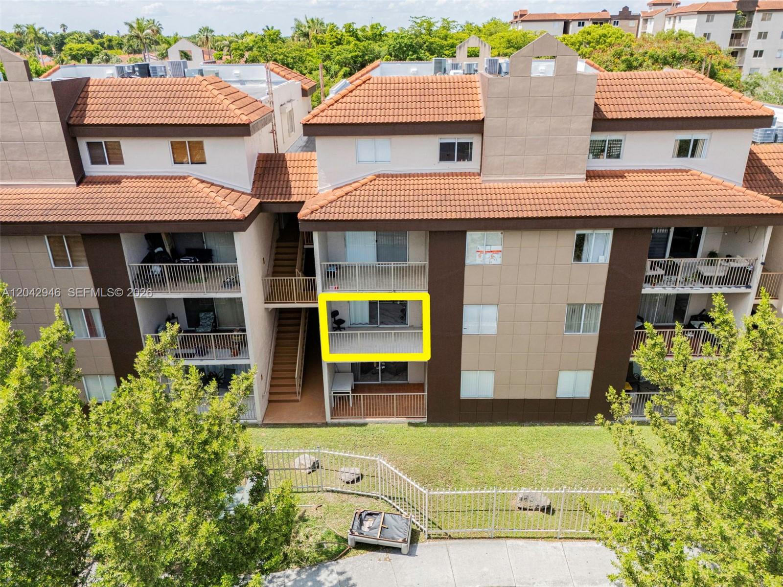 An exterior view of a multi-story apartment building with a highlighted balcony on the second floor — 15241 SW 80th St # 207, Miami FL 33193, MIAMI, FL