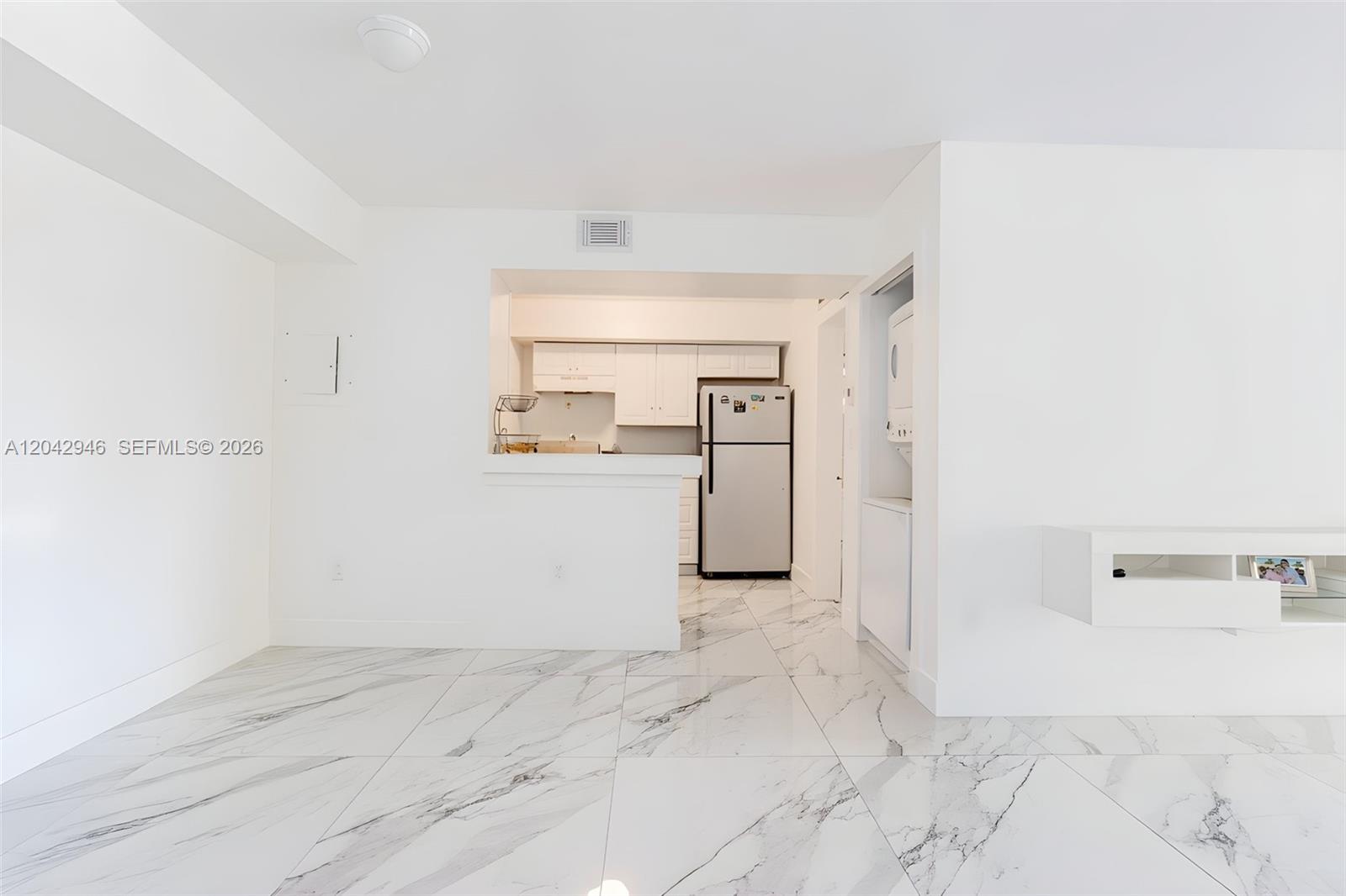 A kitchen with white cabinets and a refrigerator is visible from a tiled room — 15241 SW 80th St # 207, Miami FL 33193, MIAMI, FL