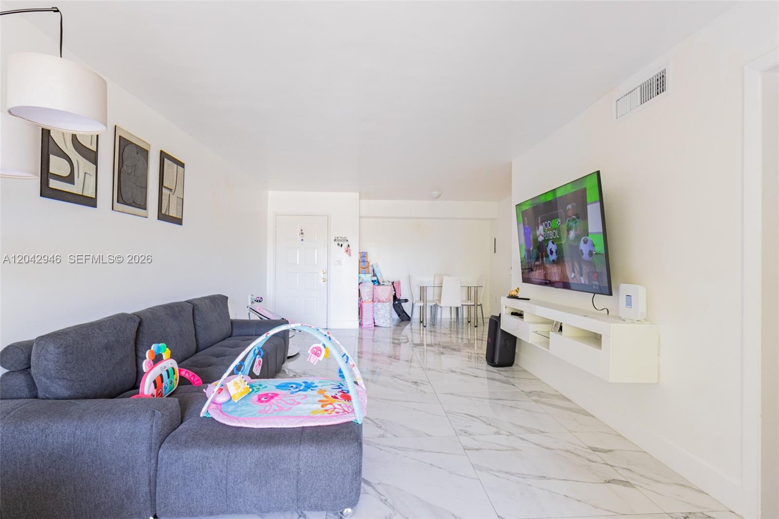 A living room features a grey sectional sofa, marble-look tile flooring, and a wall-mounted television — 15241 SW 80th St # 207, Miami FL 33193, MIAMI, FL