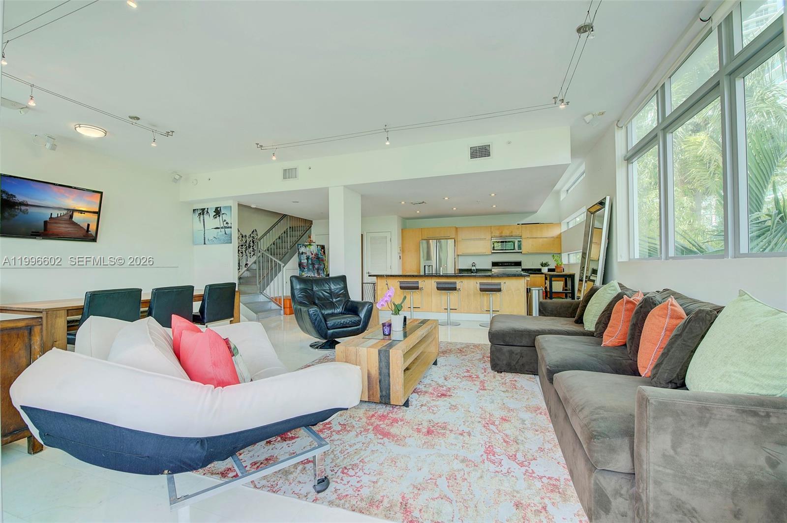 A living room with a sectional sofa, a white armchair, and an open-concept kitchen — 1577 Bay Rd # 201, Miami Beach FL 33139, MIAMI BEACH, FL