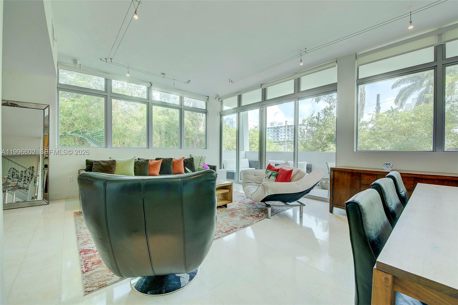 A bright living room features floor-to-ceiling windows, a large area rug, and modern furniture — 1577 Bay Rd # 201, Miami Beach FL 33139, MIAMI BEACH, FL