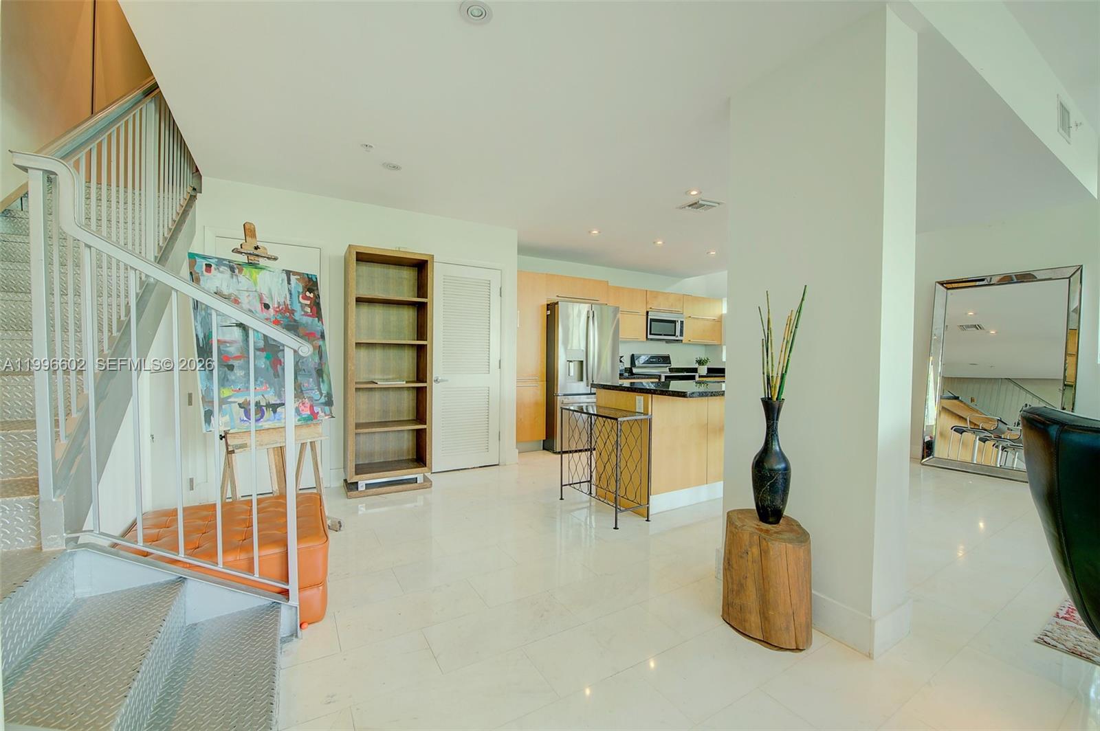 A modern open-concept kitchen features light wood cabinets, stainless steel appliances, and tile flooring — 1577 Bay Rd # 201, Miami Beach FL 33139, MIAMI BEACH, FL