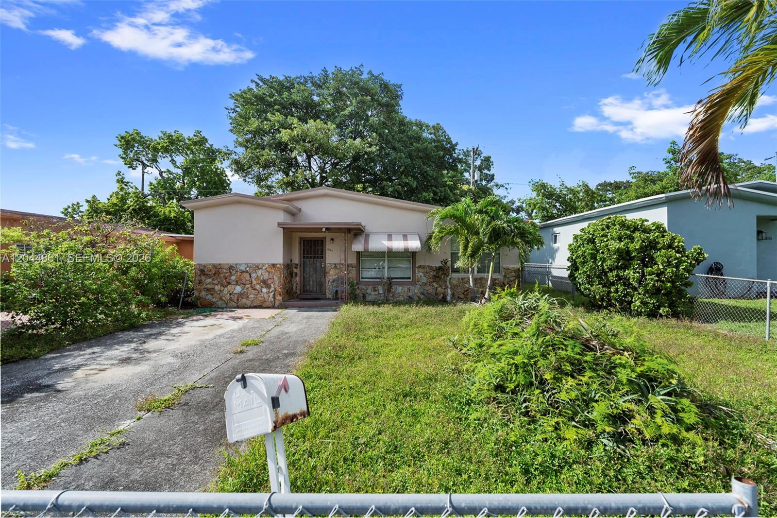 A single-story house with a stone facade, a concrete driveway, and a front yard — MIAMI, FL