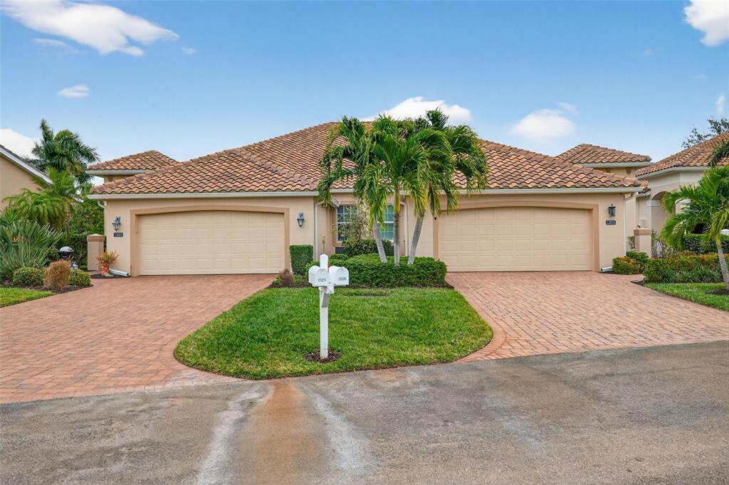 A duplex home features two garage doors, a shared driveway, and a central palm tree — 15233 CAPE SABLE LANE, FORT MYERS, FL