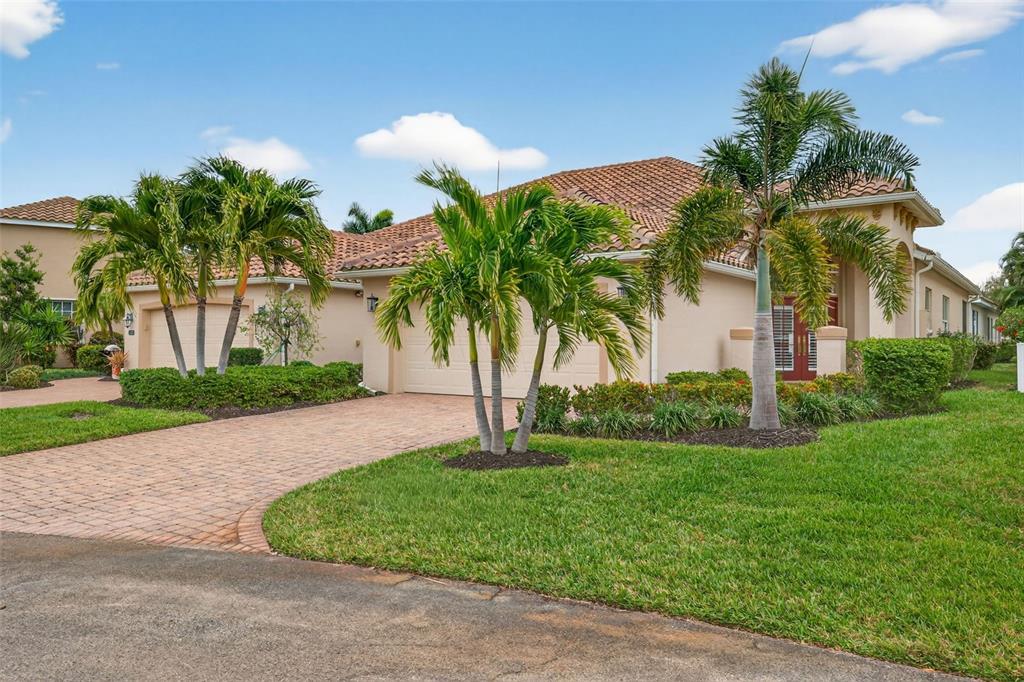 A single-story house with a tiled roof, palm trees, and a brick paver driveway — 15233 CAPE SABLE LANE, FORT MYERS, FL