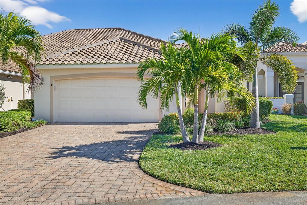 A single-story house with a beige exterior, a two-car garage, and palm trees in front — 15233 CAPE SABLE LANE, FORT MYERS, FL