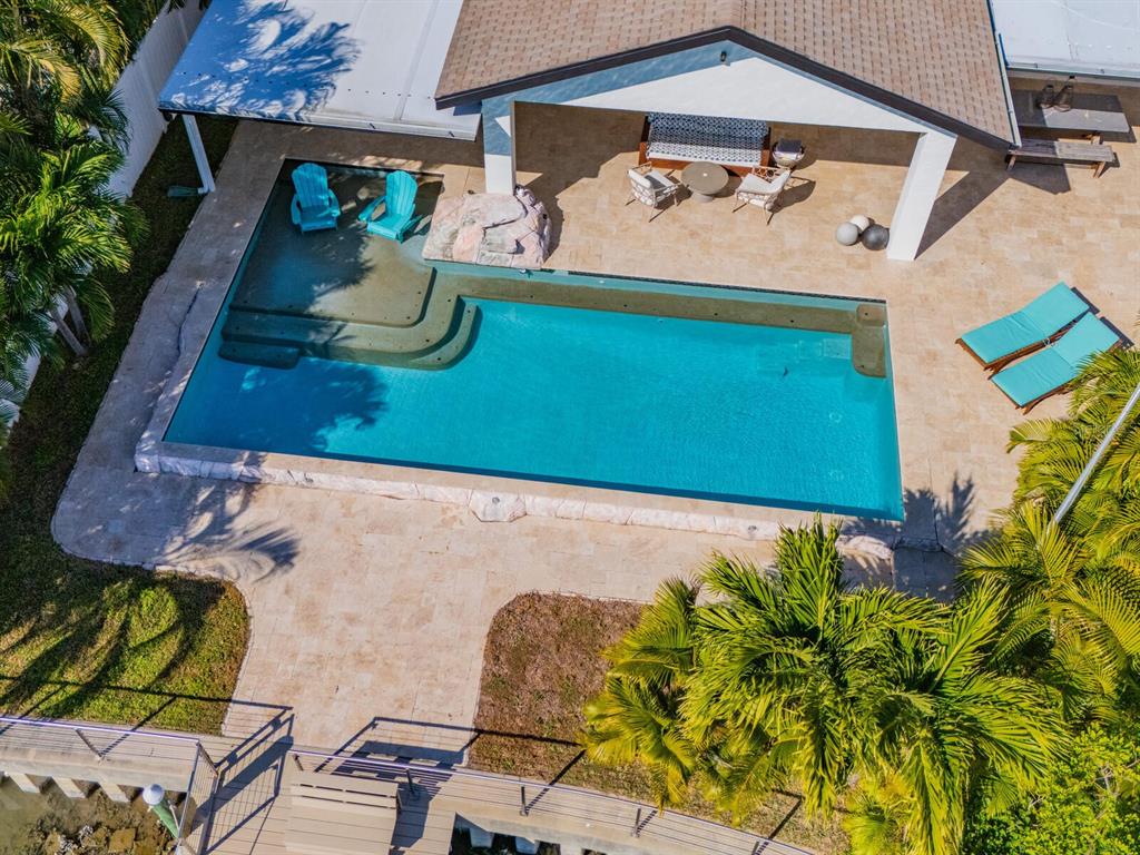 An aerial view of a backyard featuring a rectangular swimming pool, patio, and palm trees — 1028 79TH STREET S, ST PETERSBURG, FL