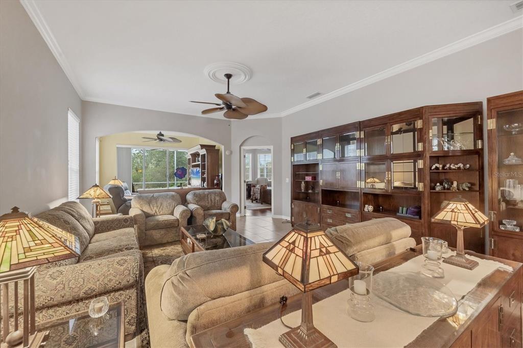 A living room features a large wooden wall unit, patterned sofas, and stained-glass lamps — 1647 LANCASHIRE DRIVE UNIT 1647, VENICE, FL