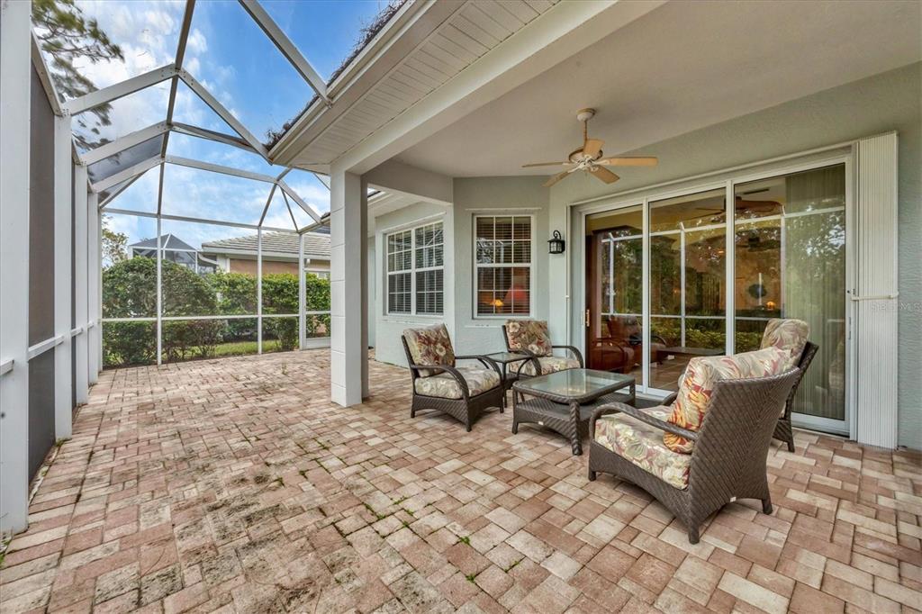 A covered patio with brick pavers, wicker furniture, and a screened-in enclosure — 1647 LANCASHIRE DRIVE UNIT 1647, VENICE, FL
