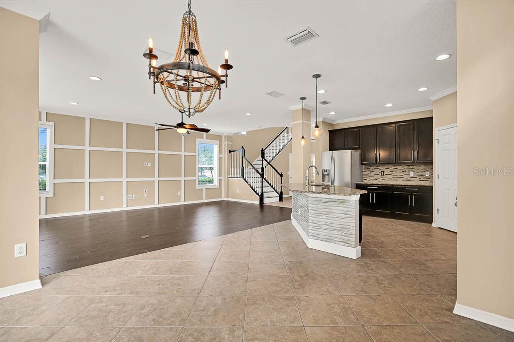 An open-concept kitchen and living area features dark wood flooring, tile, and a chandelier — 16405 EGRET CROSSING LANE, LITHIA, FL