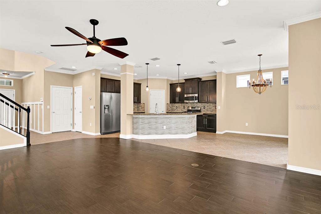 An open-concept kitchen with dark cabinetry and a breakfast bar overlooks a large living area — 16405 EGRET CROSSING LANE, LITHIA, FL