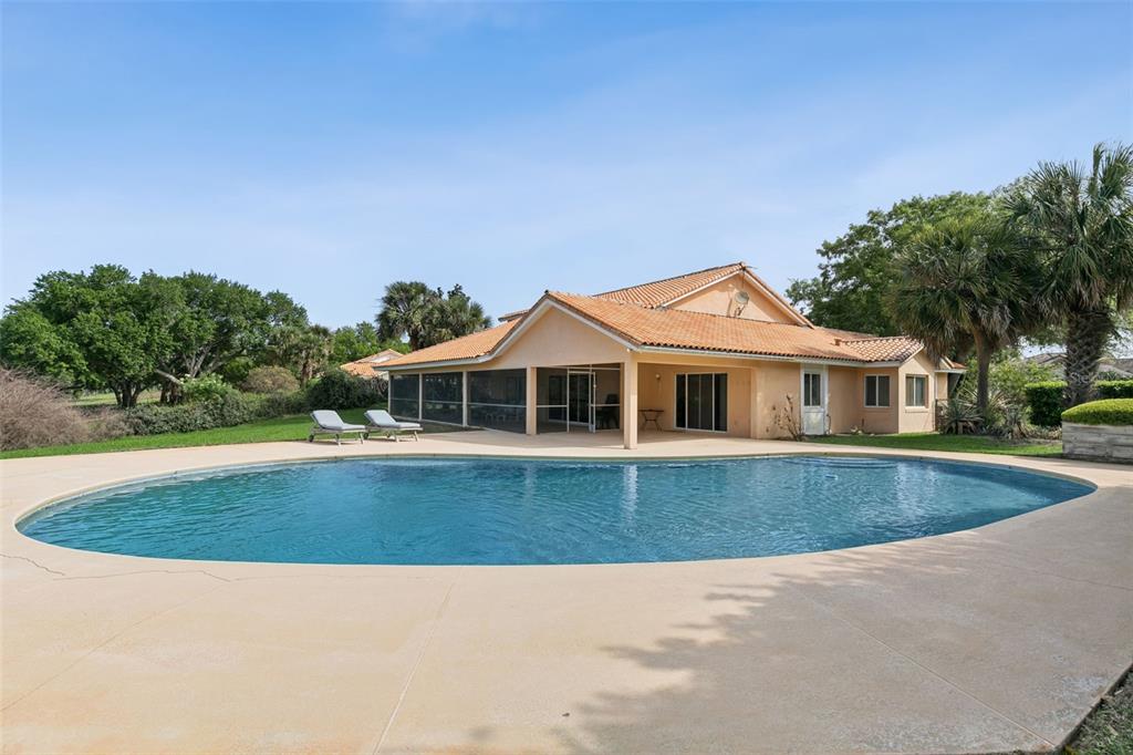 A single-story house with a tiled roof and a large swimming pool in the backyard — 12811 BELLERIVE DRIVE, CLERMONT, FL