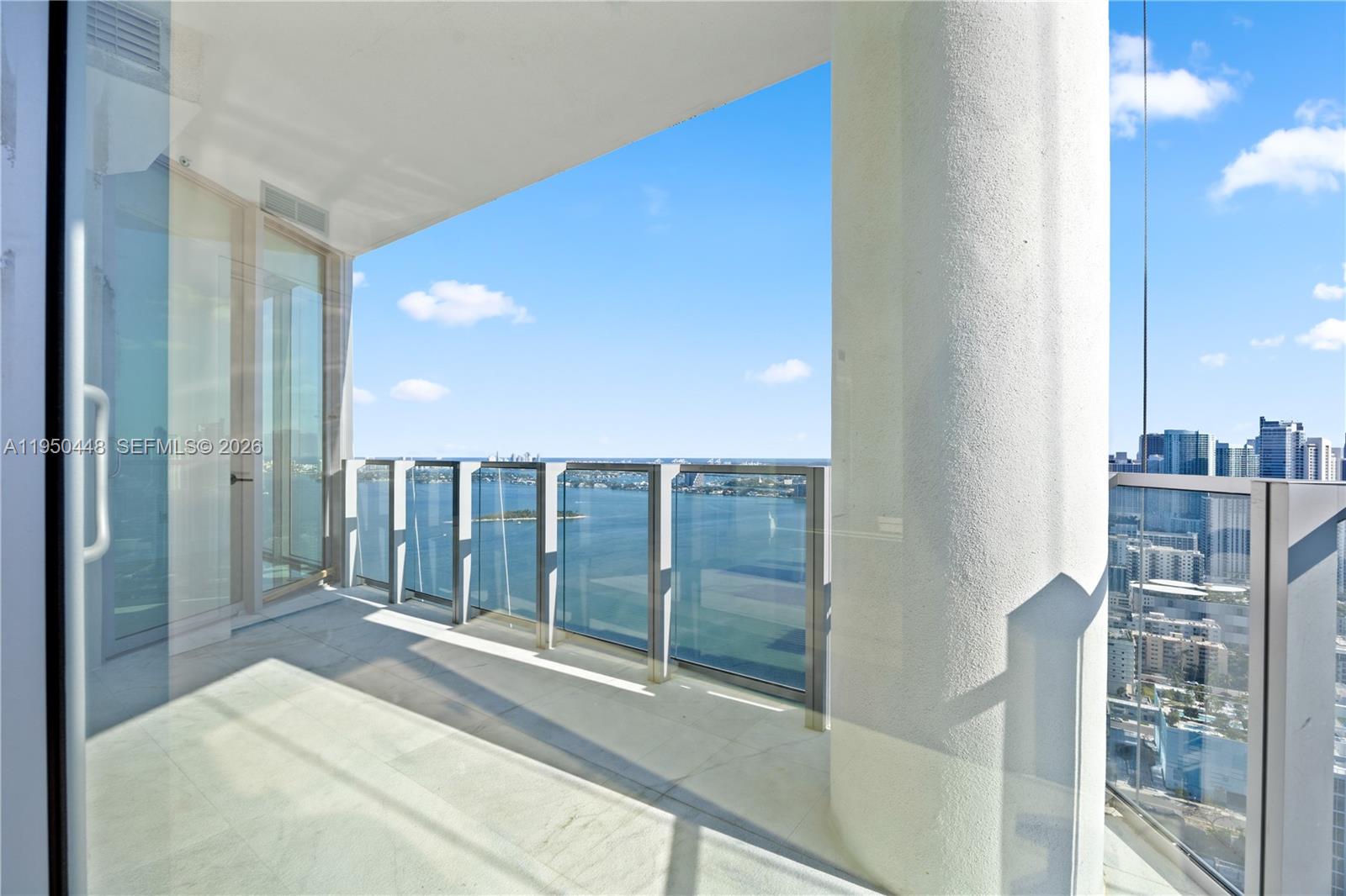 A high-rise balcony features a glass railing, a large white column, and a water view — 2900 NE 7th Ave # 4009, Miami FL 33137, MIAMI, FL
