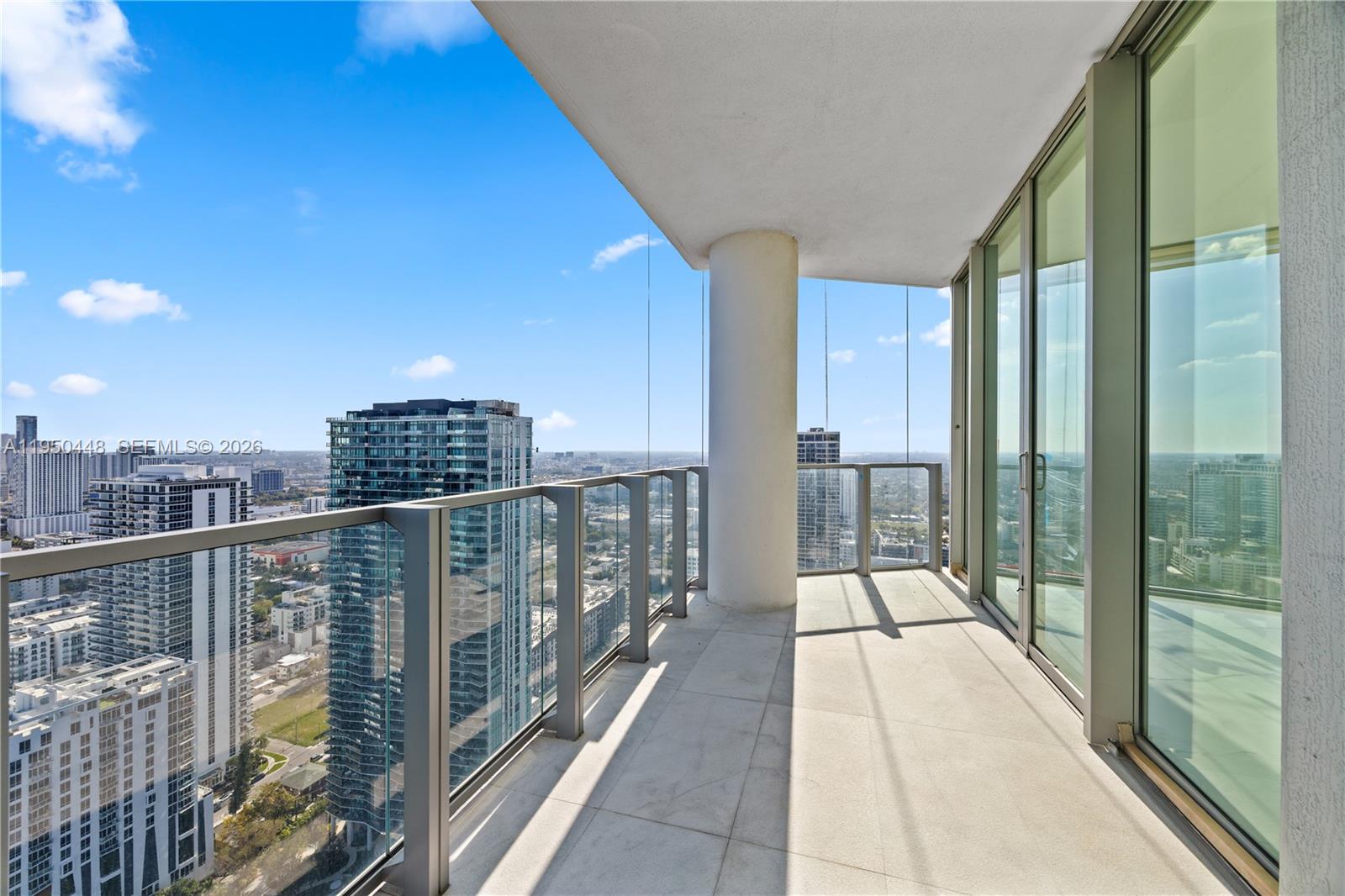 A high-rise balcony features a glass railing, concrete flooring, and panoramic city views — 2900 NE 7th Ave # 4009, Miami FL 33137, MIAMI, FL