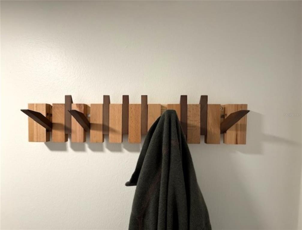 A wall-mounted wooden coat rack with several hooks holds a dark garment — 3806 GULF OF MEXICO DRIVE UNIT C305, LONGBOAT KEY, FL