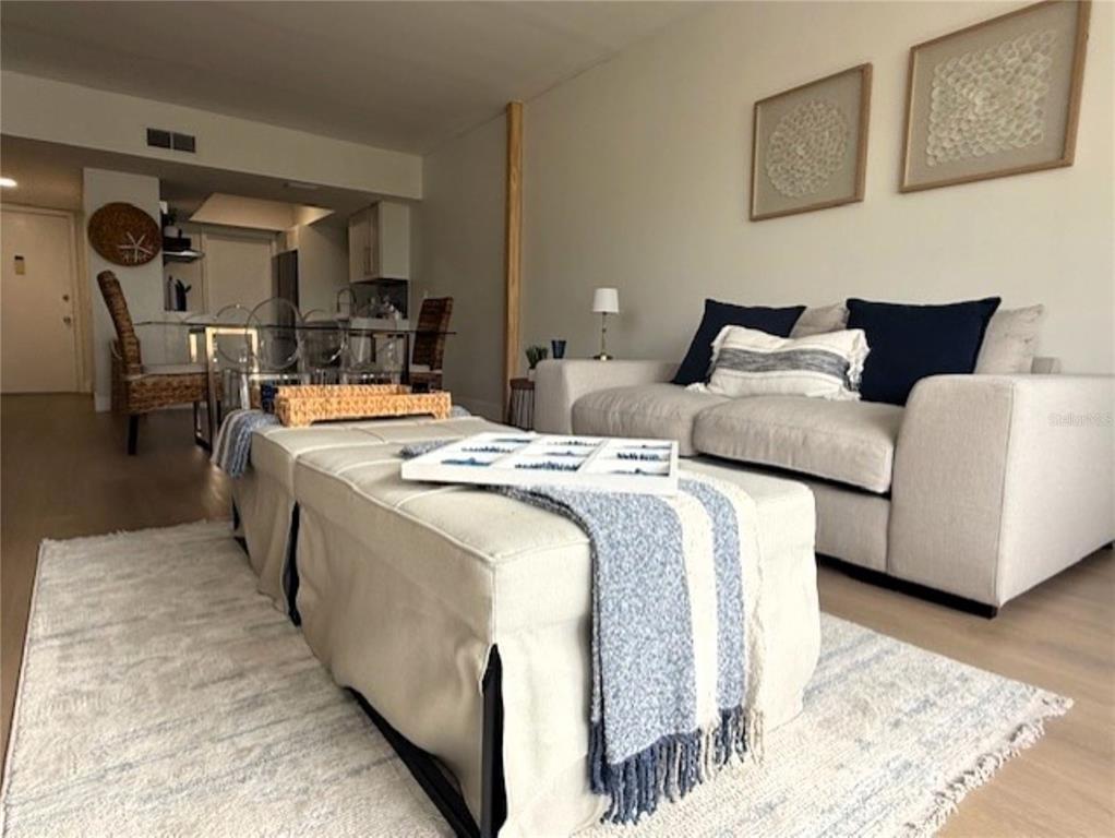 A living room features a beige sofa, a large tufted ottoman, and a dining area — 3806 GULF OF MEXICO DRIVE UNIT C305, LONGBOAT KEY, FL