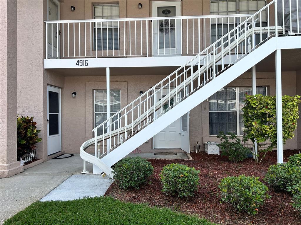 An exterior view of a two-story apartment building with white stairs and railings — 4916 SUNNYBROOK DRIVE UNIT 14, NEW PORT RICHEY, FL