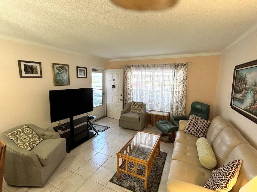 A living room features a beige sofa, two armchairs, a glass-topped coffee table, and tile flooring — 4916 SUNNYBROOK DRIVE UNIT 14, NEW PORT RICHEY, FL
