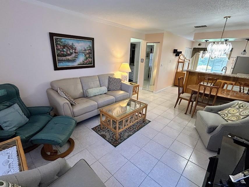 A living room with tile flooring, a beige sofa, a teal recliner, and a dining area — 4916 SUNNYBROOK DRIVE UNIT 14, NEW PORT RICHEY, FL