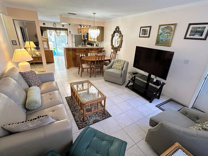 A living room with tile floors, a television, and an adjacent dining area and kitchen — 4916 SUNNYBROOK DRIVE UNIT 14, NEW PORT RICHEY, FL