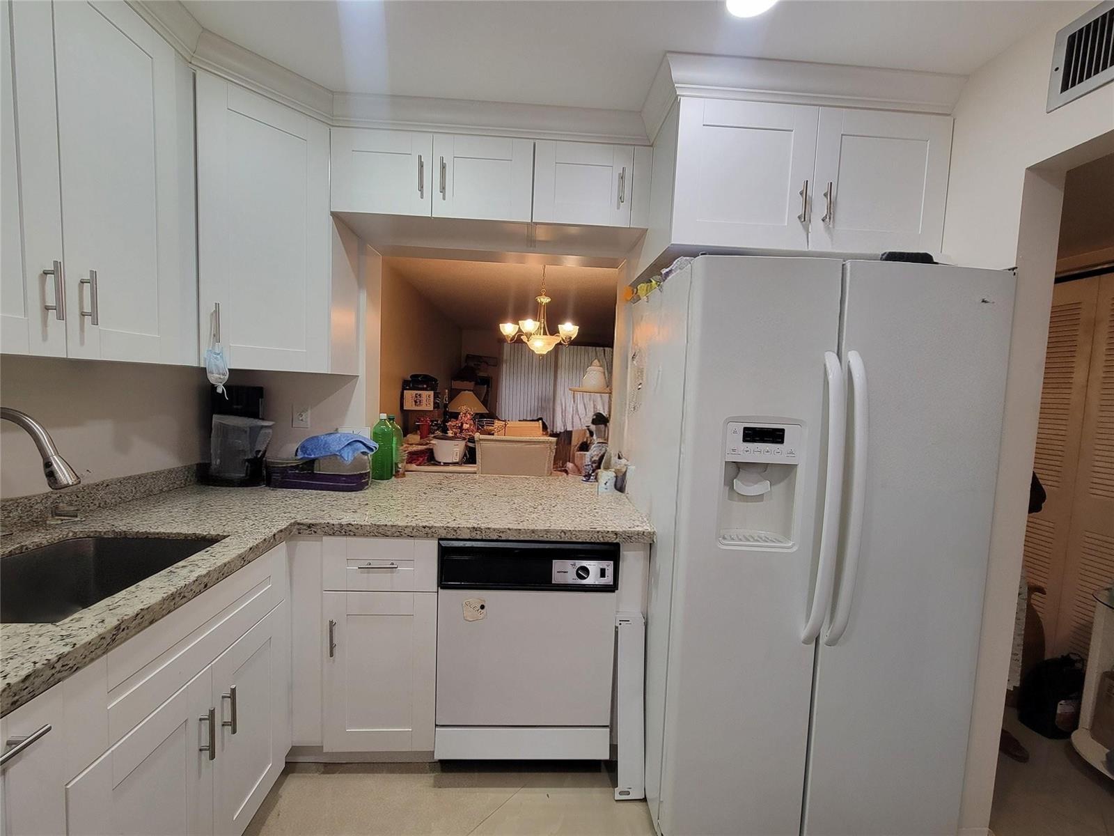 A kitchen features white cabinets, granite countertops, a dishwasher, and a white refrigerator — 5945 Del Lago Circle, Sunrise FL 33313, SUNRISE, FL