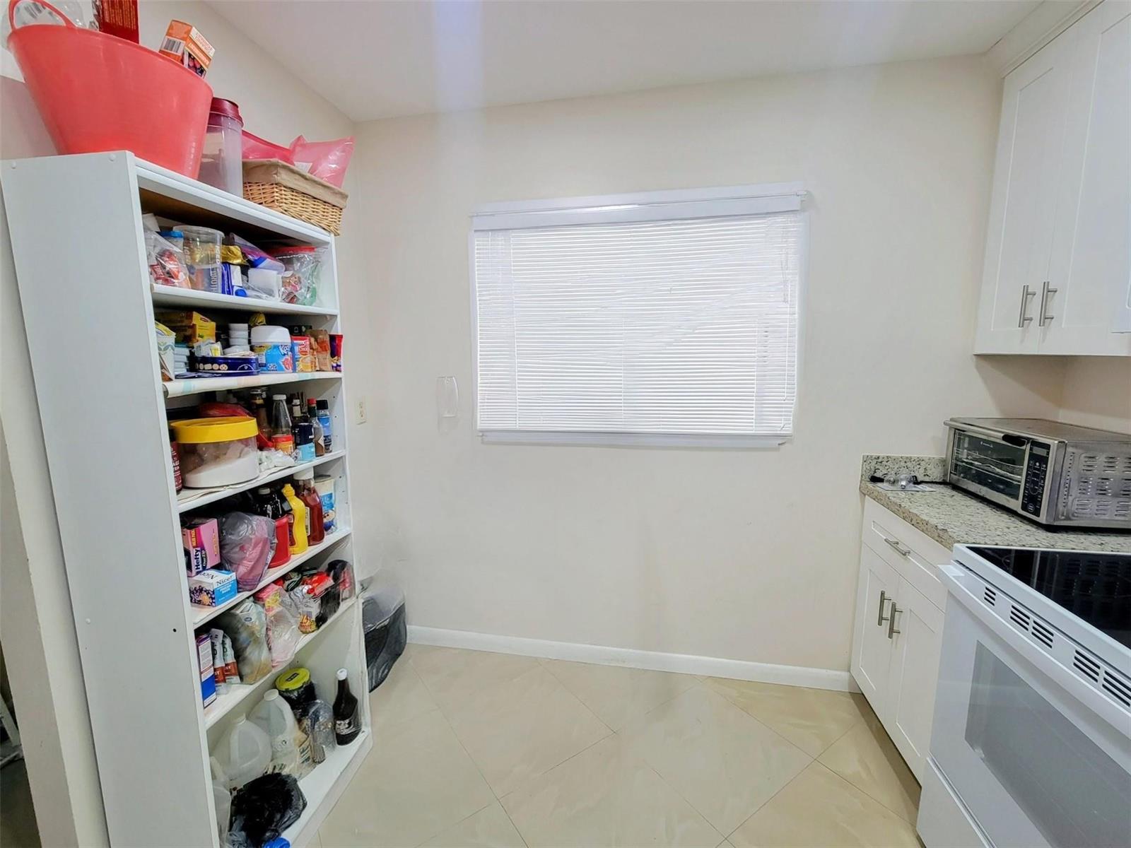 A kitchen area featuring a white open shelving unit, a window, and a white stove — 5945 Del Lago Circle, Sunrise FL 33313, SUNRISE, FL