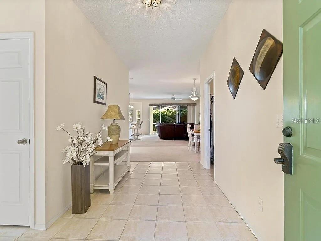 A tiled entryway leads into a living area with a console table and wall decor — 5044 45TH STREET W, BRADENTON, FL
