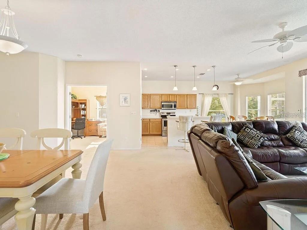 A living room and dining area open to a kitchen with wooden cabinets and island seating — 5044 45TH STREET W, BRADENTON, FL