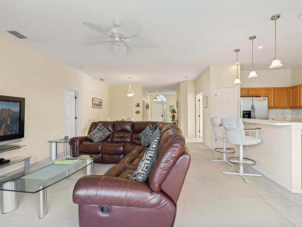A living room with a brown leather sectional sofa, glass coffee table, and adjacent kitchen — 5044 45TH STREET W, BRADENTON, FL