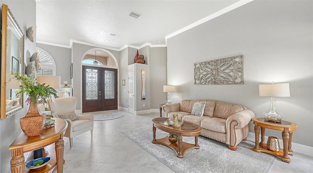 A living room features tile floors, a beige sofa, and a double front door entry — 6682 SAINT JAMES CROSSING, UNIVERSITY PARK, FL