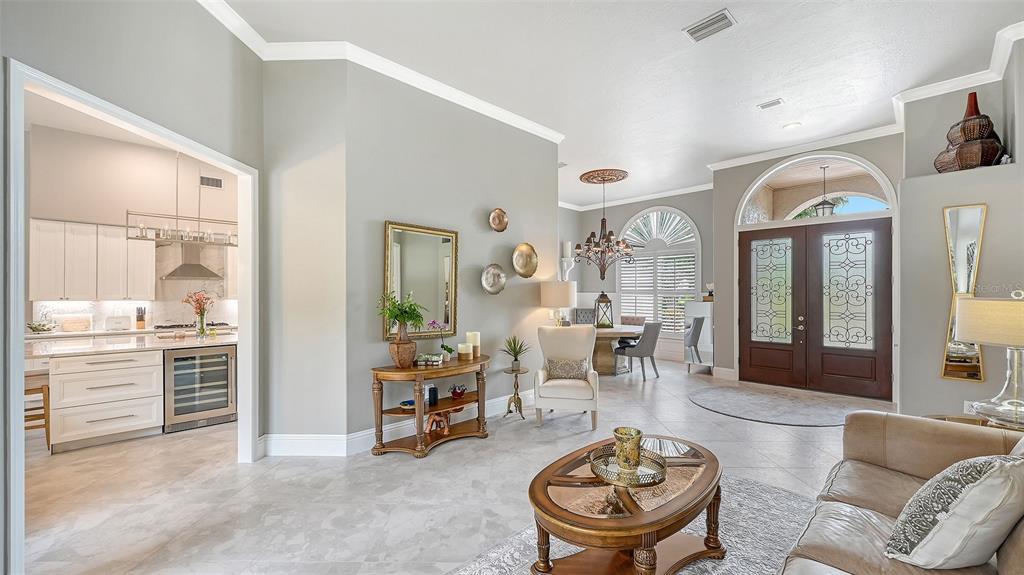 A bright open-concept living area features tile floors, a kitchen, and a formal entryway — 6682 SAINT JAMES CROSSING, UNIVERSITY PARK, FL